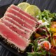 sliced ahi tuna steaks coated in sesame seeds served with lime and salad greens